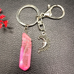 Detail of pink crystal teardrop and silver moon charm keychain on black leather