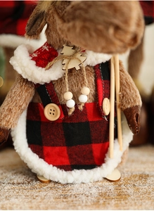 Close-up of reindeer plush decor with red plaid overalls and wooden tree detail