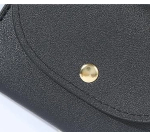 Close-up of black PU leather wallet showing stitched edges and a gold snap button