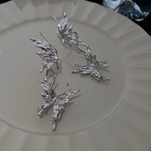 Gros plan de boucles d'oreilles papillon argentées au design en métal liquide fluide