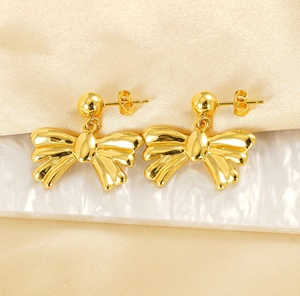 Macro shot of 18k gold plated stainless steel bow earrings on silk background