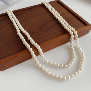 Detail of elegant double-layer pearl necklace on a rustic wooden display tray