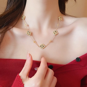 Detail of gold floral necklace with diamond pendants on a model in red sweater