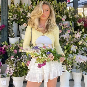 Detail of pale yellow knit cardigan paired with white layered cake skirt and white crop top