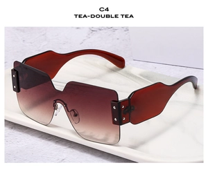 Detail view of large frame sunglasses with tea-colored lenses on marble tray