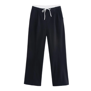 Detail view of black wide-leg trousers featuring a white layered waist and drawstring design