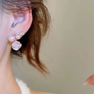 Dettaglio degli eleganti orecchini a fiore con perle rosa e pietre di zircone