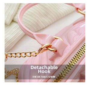 Close-up of detachable gold hook and pink jelly shell bag with metal chain strap