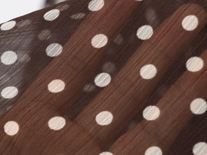 Macro shot of brown polka dot chiffon fabric with pleated texture and semi-sheer detail