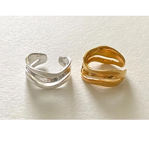 Detail view of wavy 925 sterling silver rings in gold and silver on textured paper