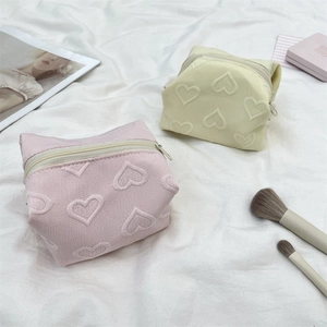 Détails de trousses cosmétiques rose et beige avec cœurs gaufrés et tissu texturé