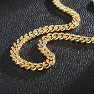 Macro detail of gold plated Cuban link chain with paved diamonds on black leather