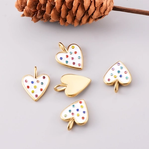 Golden heart pendants with white enamel and colorful cubic zirconia on gray background