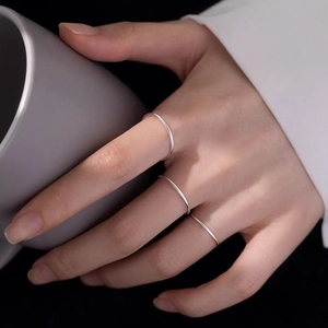 Set aus drei minimalistischen Silber-Edelstahlringen, getragen von Model mit grauem Becher
