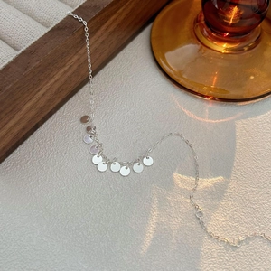 Detailed view of S925 sterling silver chain with disc pendants on a textured surface