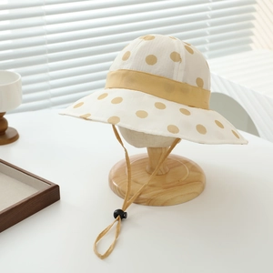 Detail of yellow polka dot sun hat showing woven texture and adjustable chin strap