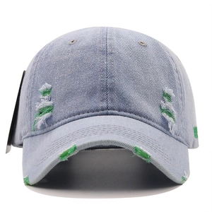 Detailed close-up of distressed denim baseball cap with torn fabric and green underlay