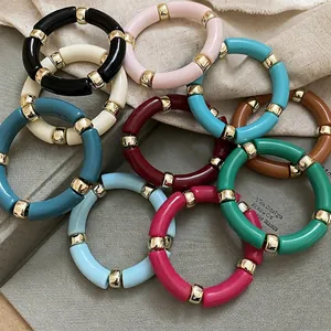 Colorful acrylic geometric tube bracelets with gold metal beads on a minimalist background