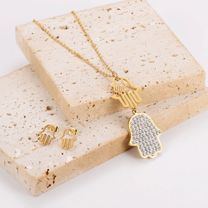 Goldenes Hamsa-Schmuckset mit funkelnden Strasssteinen auf strukturiertem Stein