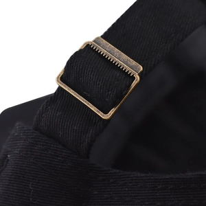 Close-up of adjustable bronze metal buckle on black cotton twill baseball cap