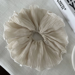 Détail du chouchou blanc surdimensionné montrant la texture en mousseline plissée sur tissu