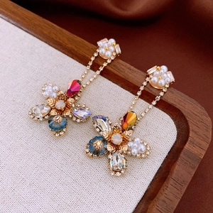 Macro detail of vintage floral earrings with colorful crystals and pearls on textured fabric