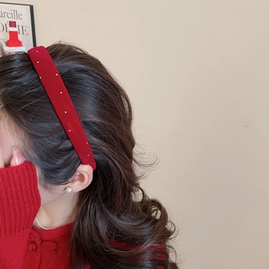 Detail of red velvet headband with white pearls worn by a model in elegant style
