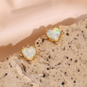 Detailed macro view of heart-shaped opal earrings with gold plating and small diamonds