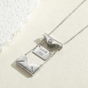 Macro shot of silver envelope locket necklace revealing an engraved Love You message
