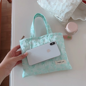 Macro view of mint green floral embossed mini bag with zipper and size reference