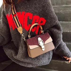Detail of color-block crossbody bag with gold round buckle and striped woven strap