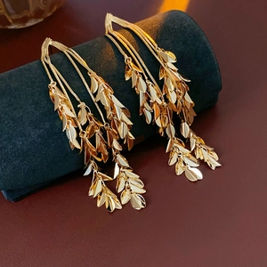 Detailed view of gold leaf tassel earrings hanging on a black velvet jewelry display stand