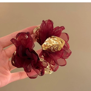 Detail of wine red chiffon flower earring featuring mesh fabric and golden metallic core