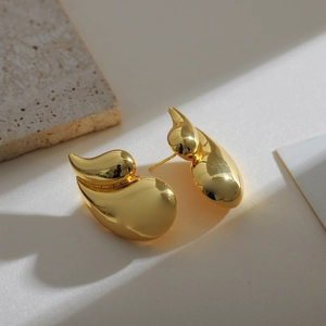 Macro detail of 18K gold teardrop earrings with a smooth polished finish on stone