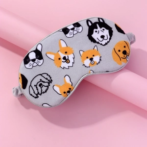 Detail of plush gray eye mask featuring cute cartoon dog patterns on a pink podium