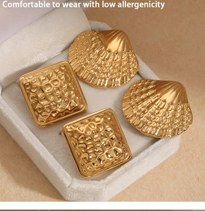 Detail of square hammered and shell texture gold earrings in jewelry display box