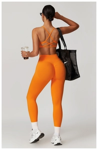 Detail of high-waisted orange yoga leggings and cross-back sports bra with supportive fit