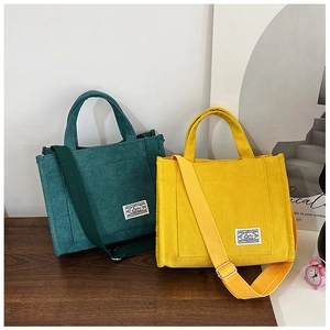 Detail view of corduroy handbags with adjustable shoulder straps in green and yellow