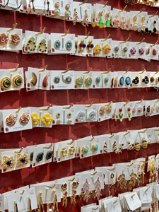 Assorted vintage bow and pearl earrings in various colors displayed on a red wall