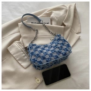 Detail of tweed denim chain bag showing blue checkered texture and frayed edges