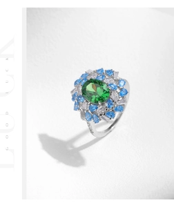 Macro detail of S925 silver ring featuring an oval green emerald and blue floral halo