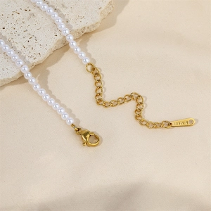 Detail of stainless steel clasp and white pearls on a gold plated O-chain necklace