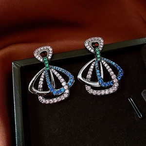 Détail de boucles d'oreilles vintage géométriques avec zircons colorés en boîte à bijoux