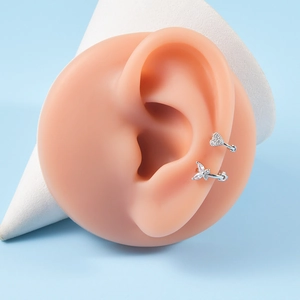 Close-up of heart and butterfly ear cuffs set with cubic zirconia on ear model