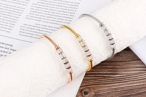 Détail de bracelets en acier titane rose, or et argent présentés sur un support blanc