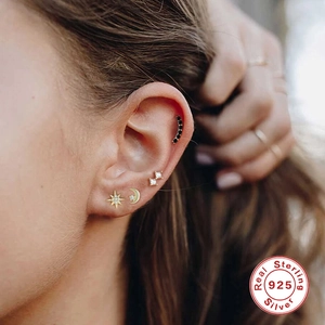 Detail view of S925 sterling silver star, moon and diamond stud earrings on ear