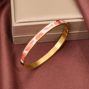 Macro shot of gold enamel bracelet with pink and white patterns on brown silk fabric