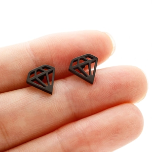 Macro detail of black diamond-shaped matte stud earrings held on a finger for size scale