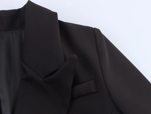 Detailed close-up of a black double-breasted blazer with notched lapels and smooth fabric