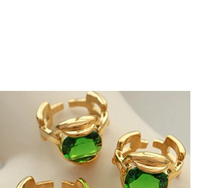 Macro shot of adjustable gold fox ring featuring green gemstones and leaf textures